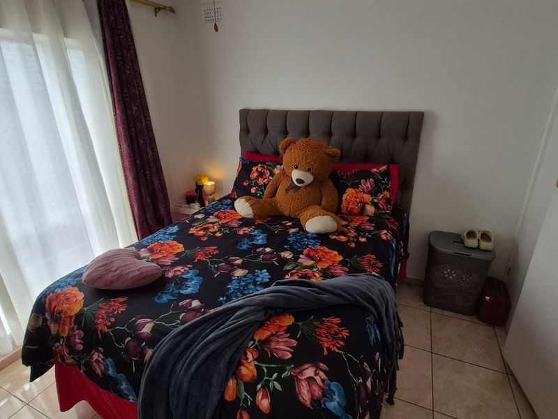 A bedroom featuring tiled flooring and a sliding glass door providing natural light, with a built-in cupboard for storage.