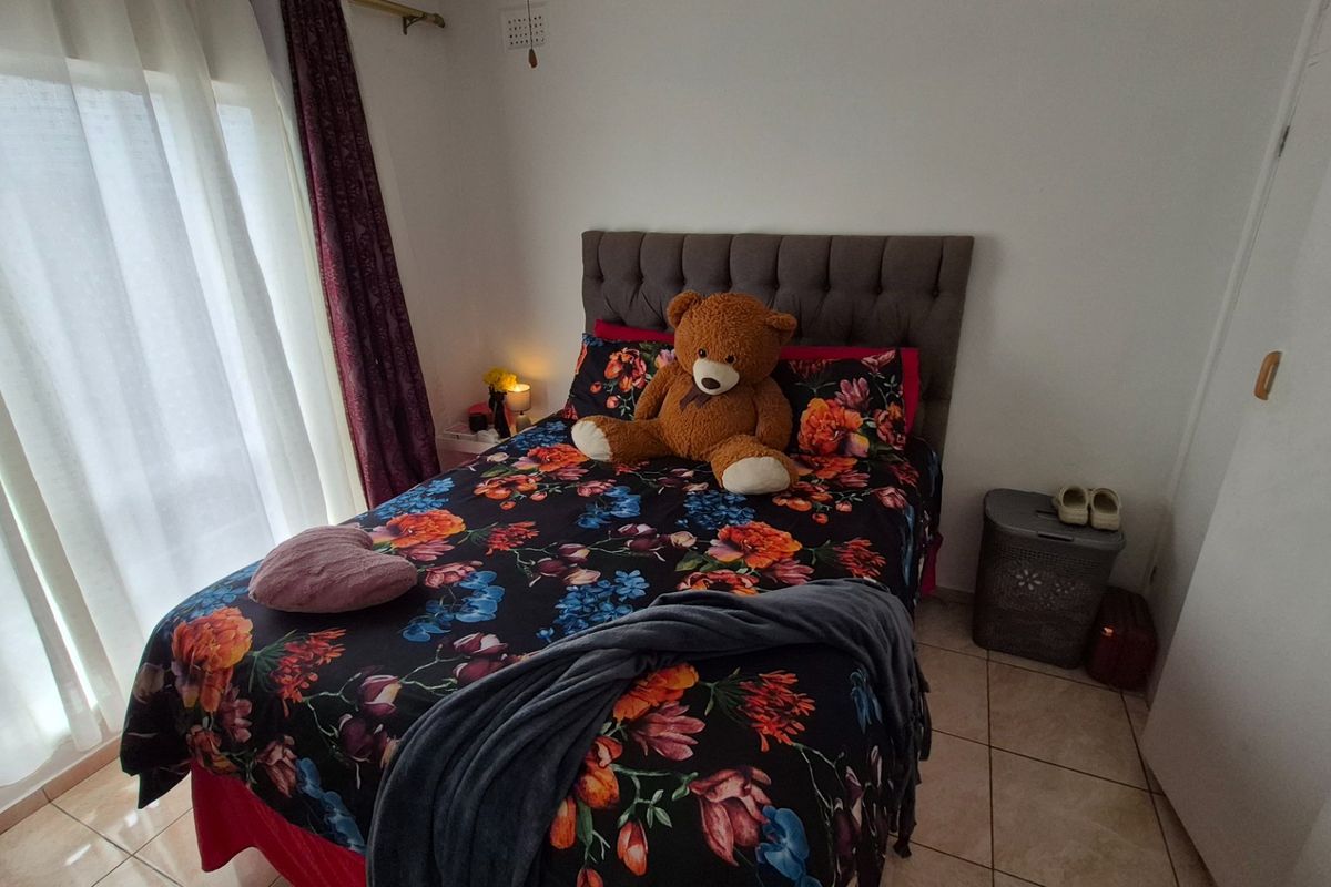 A bedroom featuring tiled flooring and a sliding glass door providing natural light, with a built-in cupboard for storage.