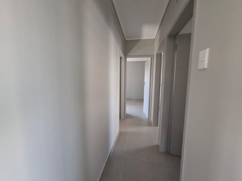 A clean, neutral-toned hallway with tiled flooring, providing access to multiple rooms within the townhouse.