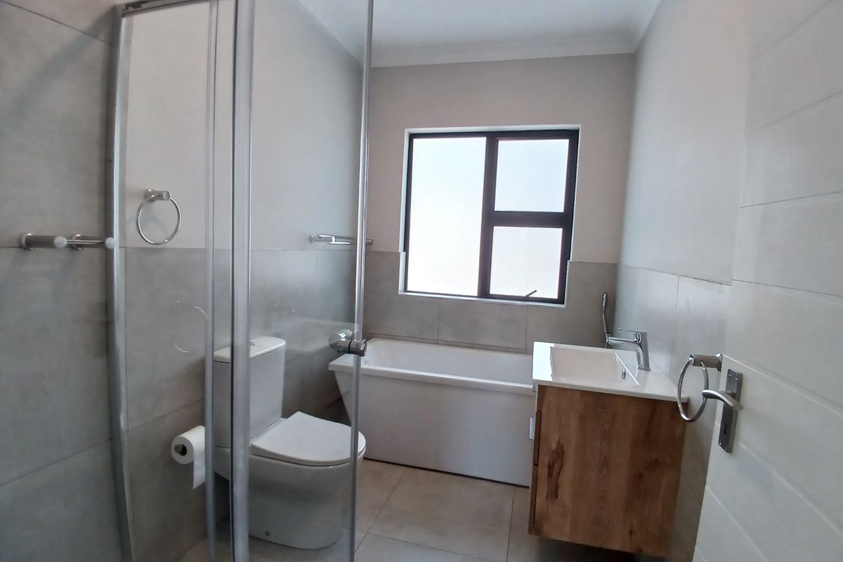 Modern bathroom featuring a glass-enclosed shower, a built-in bathtub, and a contemporary wall-mounted vanity with a ceramic basin.