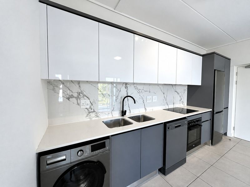 Modern kitchen featuring sleek grey and white cabinetry, marble-look splashback, integrated appliances, and high-quality finishes throughout.