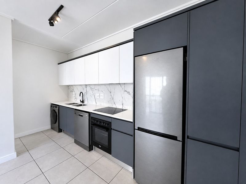Modern kitchen featuring sleek two-tone cabinetry, marble-look splashback, integrated appliances, and contemporary track lighting.