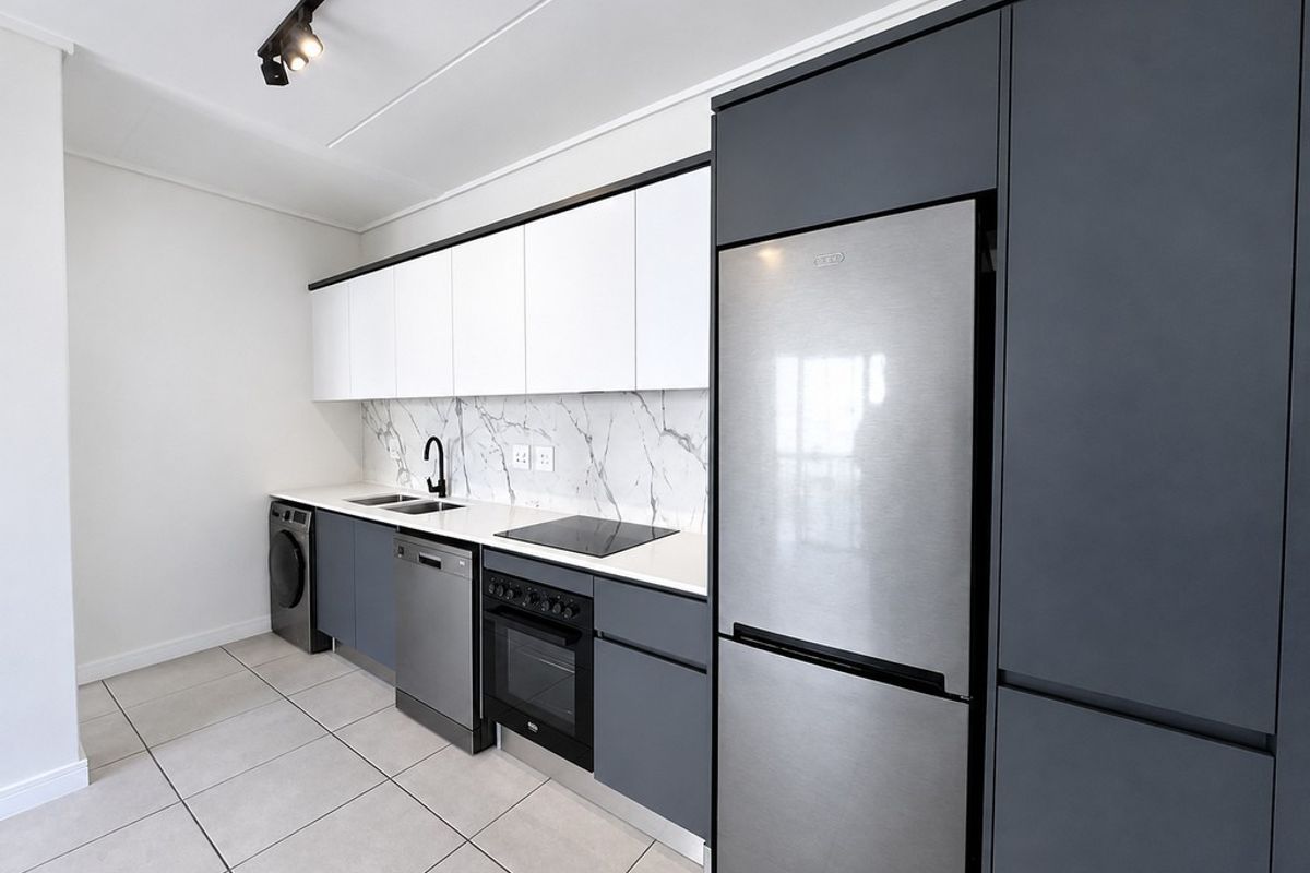 Modern kitchen featuring sleek two-tone cabinetry, marble-look splashback, integrated appliances, and contemporary track lighting.