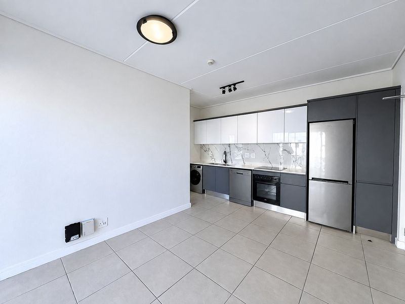 Modern open-plan kitchen featuring sleek two-tone cabinetry, marble-look splashback, integrated appliances, and neutral tiled flooring in a clean, contemporary apartment setting.