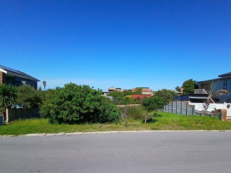 A vacant residential plot situated between existing properties, featuring established boundary walls and street-level access in a developed neighborhood.
