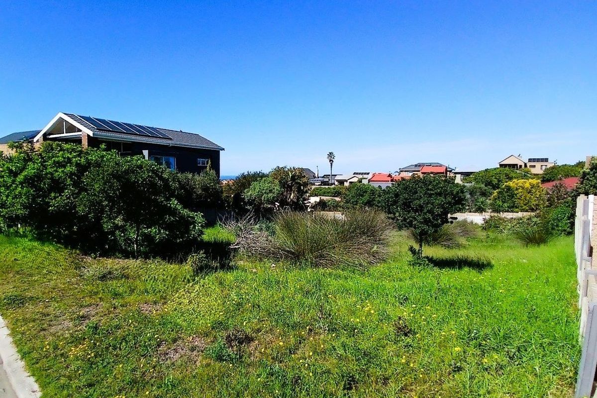 A view of a vacant residential plot featuring natural grass coverage and surrounding neighborhood infrastructure.