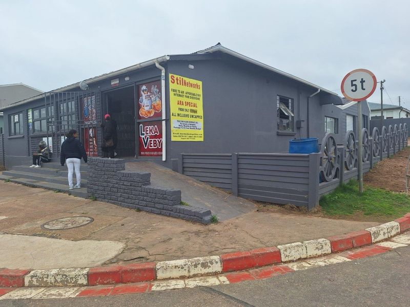 Front exterior view of a commercial building featuring a concrete access ramp, security gate, and decorative perimeter fencing.