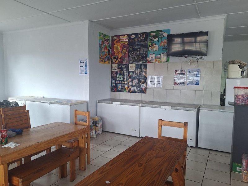 Commercial open-plan space featuring tiled flooring, tiled splashback areas, and a drop ceiling, currently utilized as a retail or dining service area.