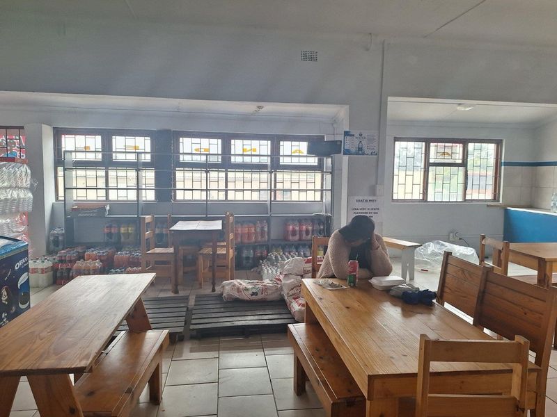 Open-plan commercial space featuring tiled flooring, large windows providing natural light, and integrated shelving units suitable for retail or dining use.