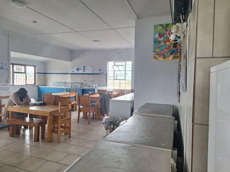 Open plan commercial space featuring tiled flooring, drop ceiling, and security bars on windows, suitable for a cafe or dining area.
