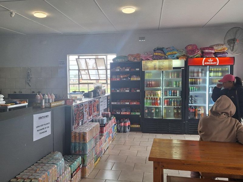 Commercial open-plan retail space featuring a service counter, tiled flooring, and built-in refrigeration units for beverage display.