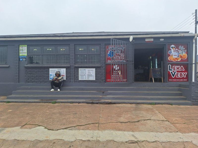 Front exterior view of a commercial takeaway shop featuring a brick facade, concrete entrance steps, and prominent business signage.