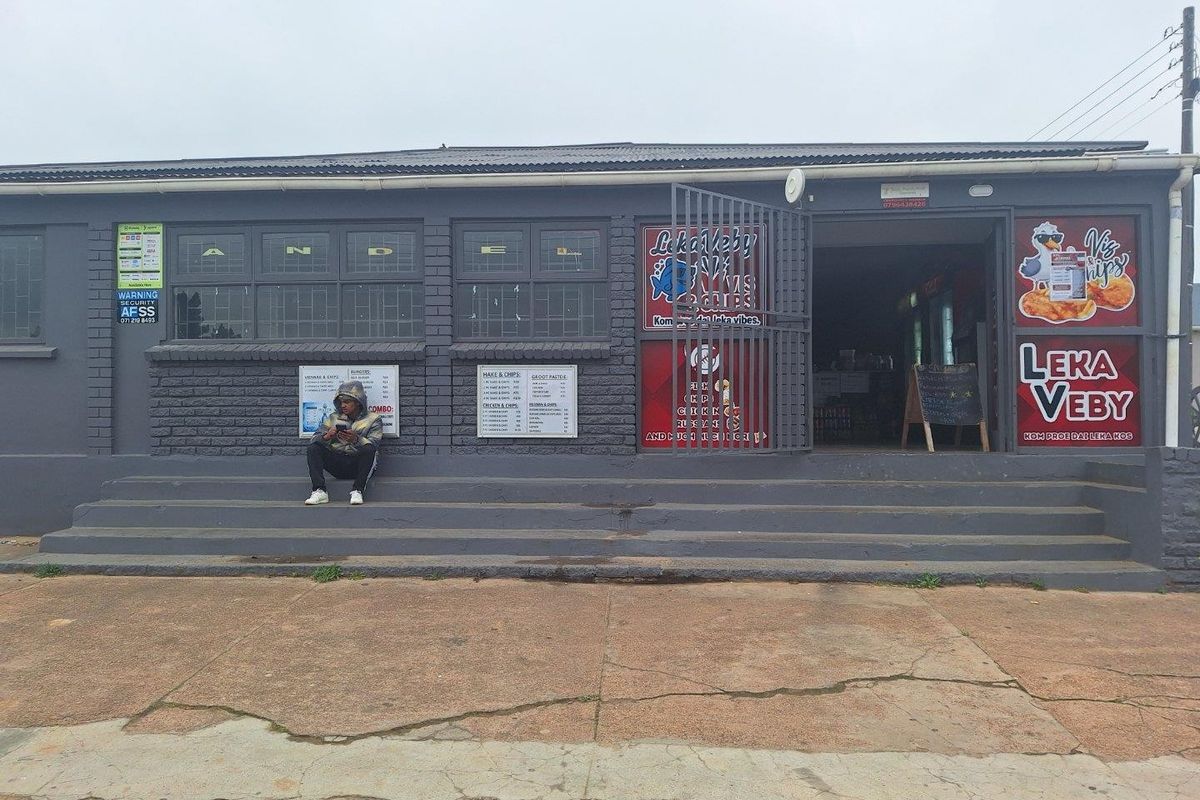 Front exterior view of a commercial takeaway shop featuring a brick facade, concrete entrance steps, and prominent business signage.