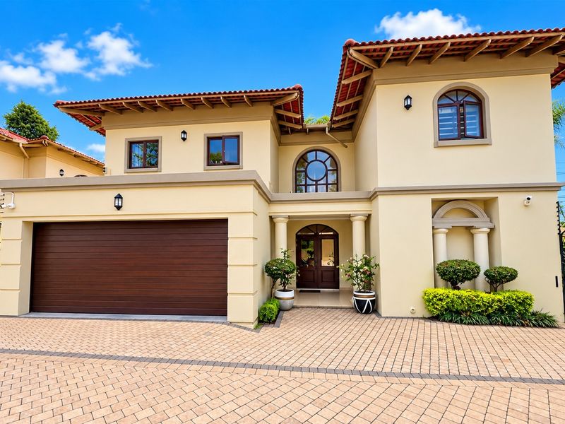 A well-maintained double-story residence featuring a paved driveway, integrated double garage, and an elegant arched entrance with classic architectural detailing.