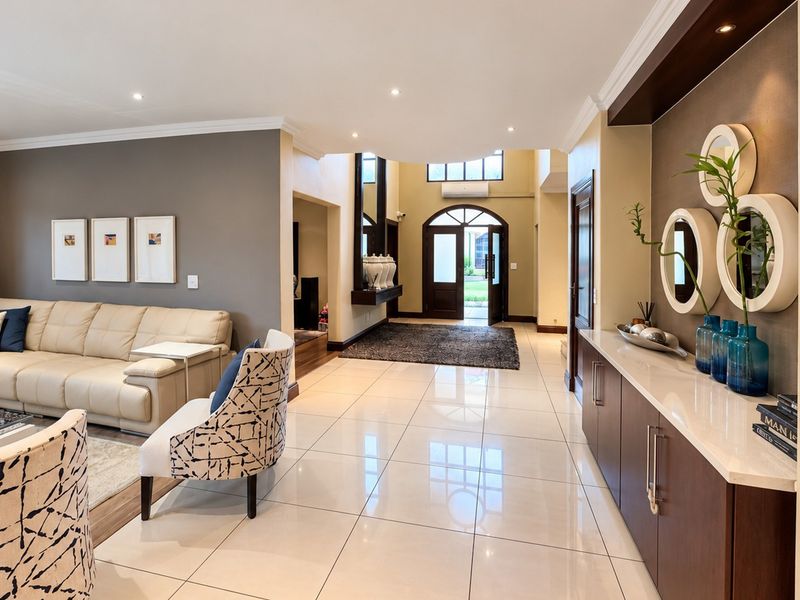 Spacious living area featuring polished porcelain tiles, recessed lighting, and custom built-in cabinetry with stone countertops, leading to a grand arched entrance.