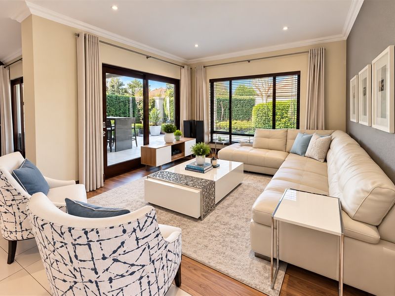 A bright and well-maintained living room featuring timber flooring, recessed lighting, and large sliding glass doors that open onto an outdoor patio area.