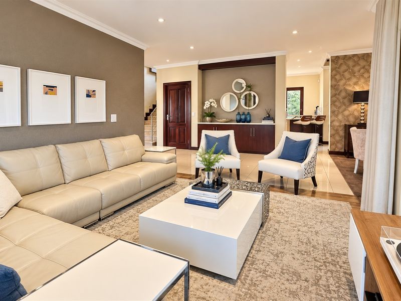 Spacious open-plan living area featuring neutral tones, recessed lighting, tiled flooring, and elegant built-in cabinetry, creating a seamless flow between living and dining spaces.