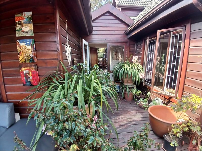 A rustic timber-clad patio area featuring wooden decking and large casement windows, providing a cozy outdoor transition space between building sections.
