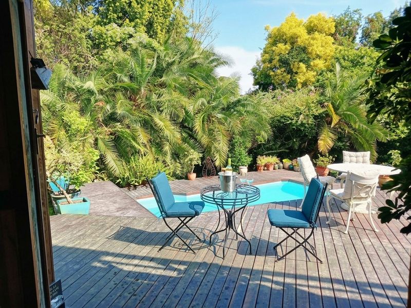 Outdoor pool area featuring a swimming pool surrounded by timber decking and lush garden landscaping.