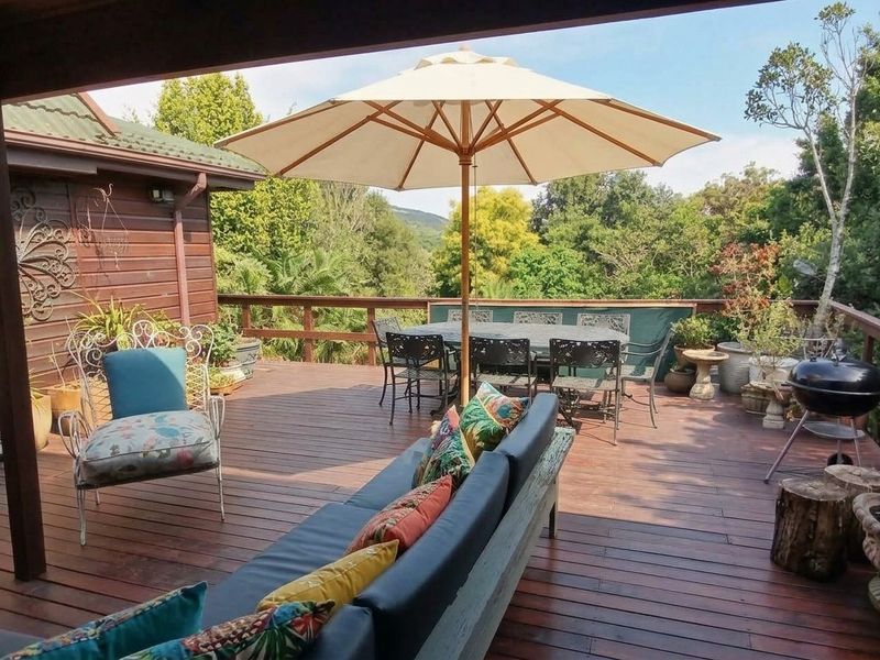 Spacious elevated timber deck featuring wooden balustrades and exterior timber cladding, offering a pleasant outdoor entertainment area with garden views.