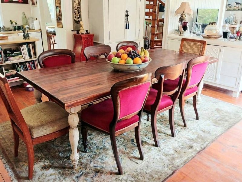 A warm and inviting dining room featuring timber flooring and built-in cabinetry, with an open-plan flow leading to the staircase area.
