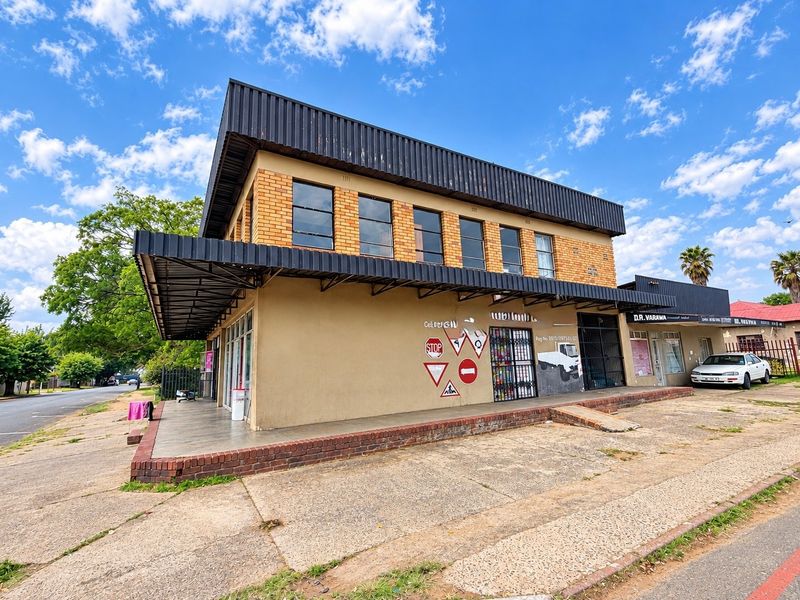 Commercial building exterior featuring a brick facade, metal awning, and paved frontage with visible signs of wear and graffiti.