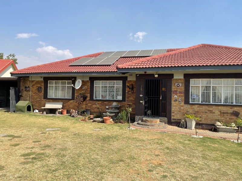 Front view of a single-story brick house featuring a tiled roof with installed solar panels, security gates, and a well-maintained front lawn.