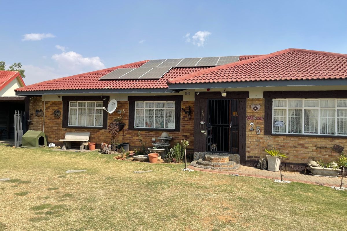 Front view of a single-story brick house featuring a tiled roof with installed solar panels, security gates, and a well-maintained front lawn.