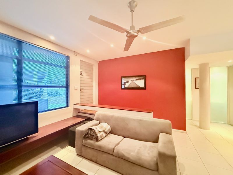 Living room featuring tiled flooring, a ceiling fan, recessed lighting, and built-in shelving against a red accent wall.