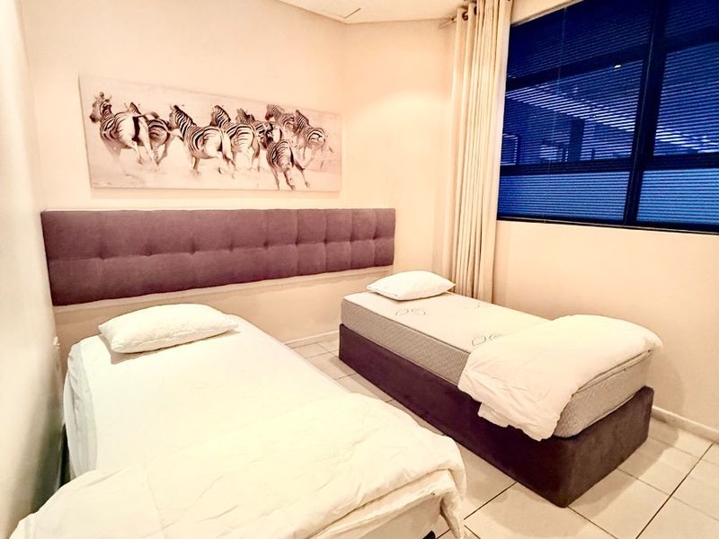 A well-lit bedroom featuring tiled flooring, a ceiling fan, and a large window with integrated blinds, providing a comfortable and functional living space.