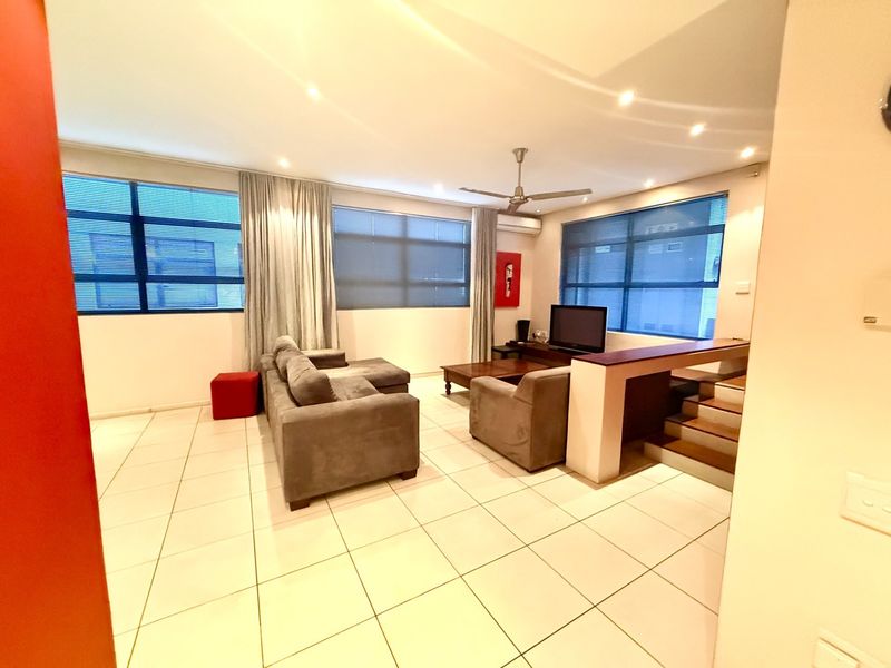 Spacious living area featuring tiled flooring, recessed downlights, a ceiling fan, split system air conditioning, and a staircase leading to another level.