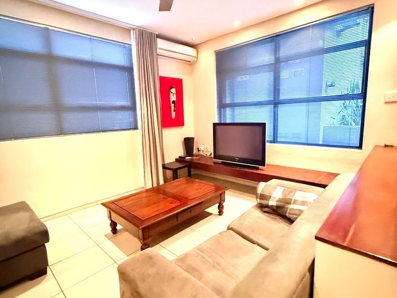 A comfortable living room featuring tiled flooring, a ceiling fan, split-system air conditioning, and a built-in wooden media console.
