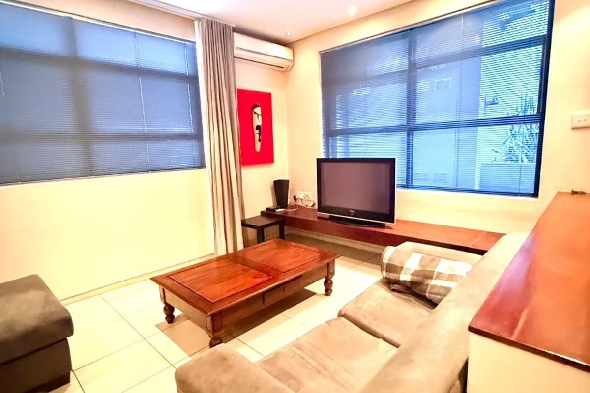 A comfortable living room featuring tiled flooring, a ceiling fan, split-system air conditioning, and a built-in wooden media console.