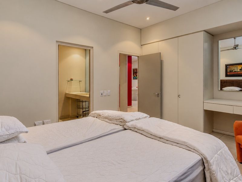 A well-maintained bedroom featuring built-in cupboards, a vanity area, ceiling fan, and direct access to an en-suite bathroom.