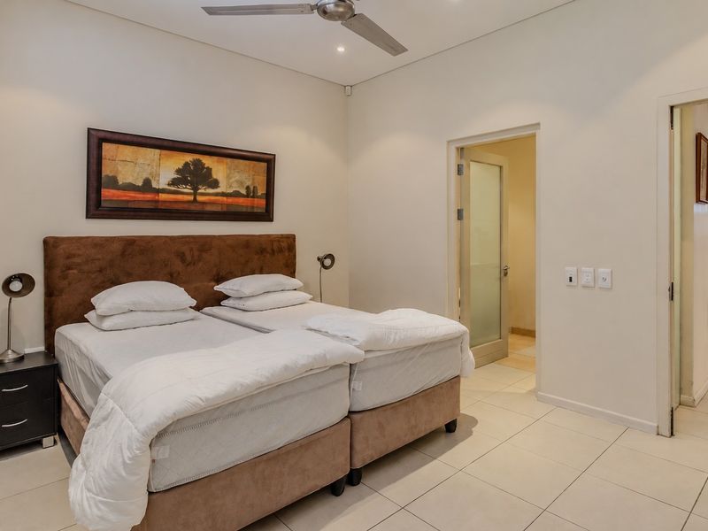 A well-maintained bedroom featuring tiled flooring, a ceiling fan, and direct access to an en-suite bathroom.