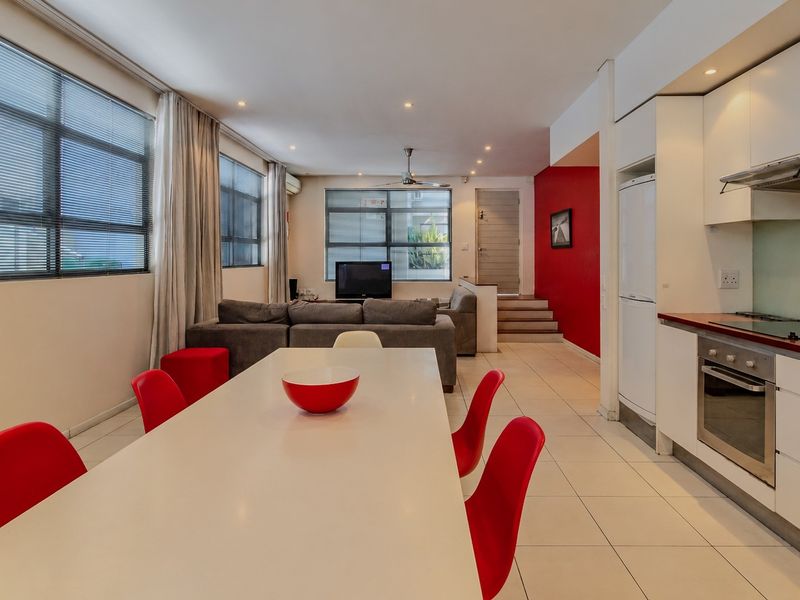 Spacious open-plan living and dining area featuring a modern kitchen with built-in appliances, tiled flooring, and large windows providing ample natural light.