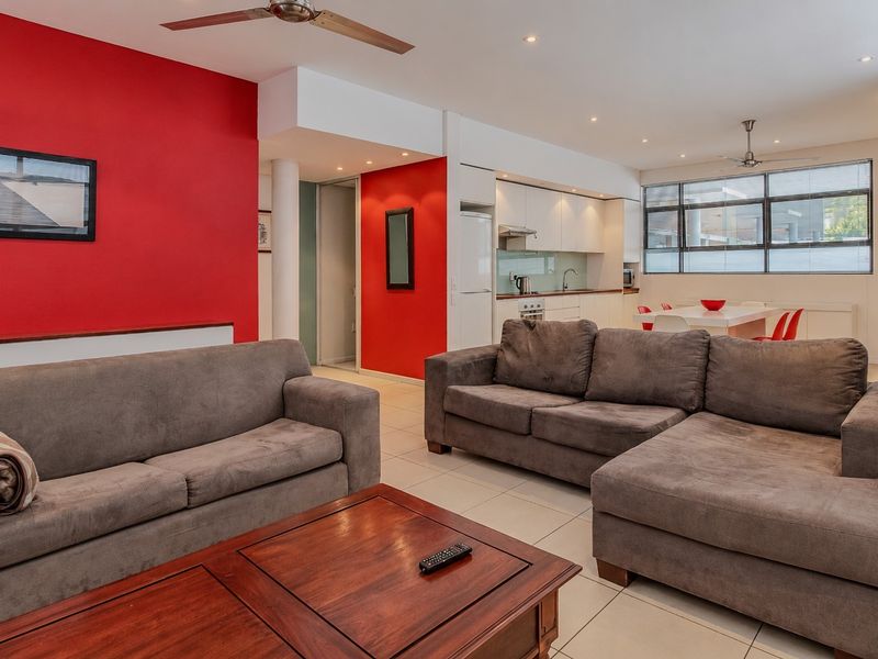 Open-plan living and kitchen area featuring tiled flooring, recessed lighting, ceiling fans, and a functional kitchen with built-in cabinetry and integrated appliances.