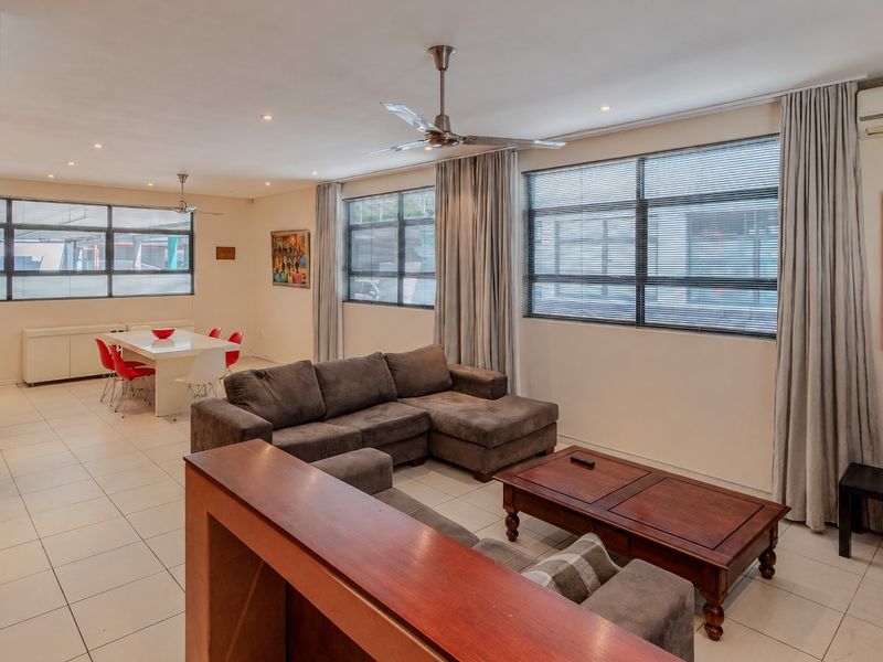 Spacious open-plan living and dining area featuring tiled floors, recessed lighting, ceiling fans, and large windows with integrated air conditioning.