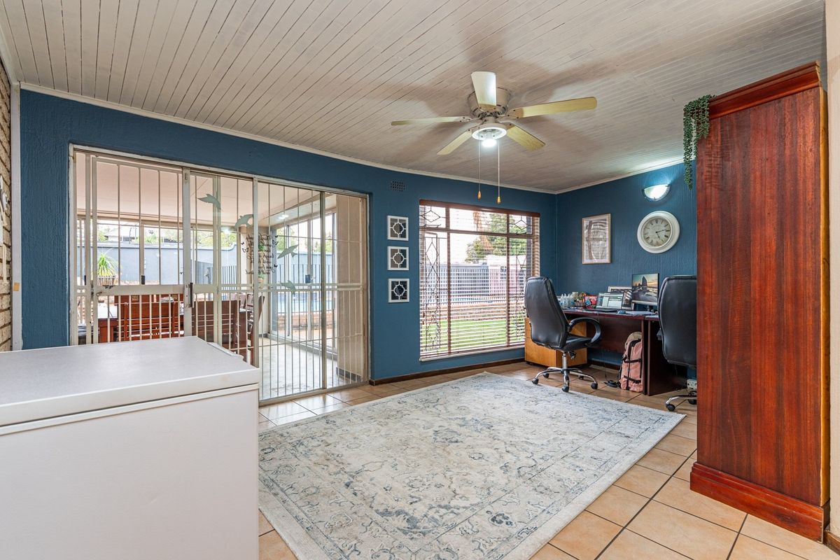 Spacious living area featuring tiled floors, a ceiling fan, and sliding glass doors leading to an enclosed patio area.