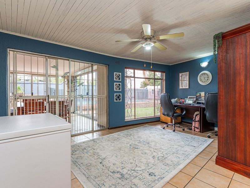 Spacious living area featuring tiled floors, a ceiling fan, and sliding glass doors leading to an enclosed patio area.