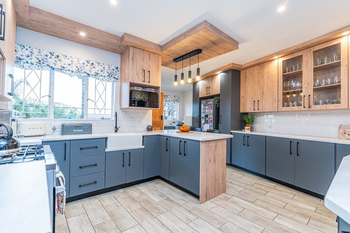 Modern kitchen featuring two-tone cabinetry, quartz countertops, a farmhouse sink, gas hob, and stylish timber-look ceiling accents with integrated lighting.