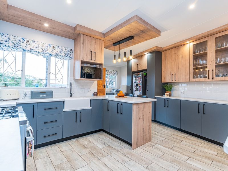 Modern kitchen featuring two-tone cabinetry, quartz countertops, a farmhouse sink, gas hob, and stylish timber-look ceiling accents with integrated lighting.