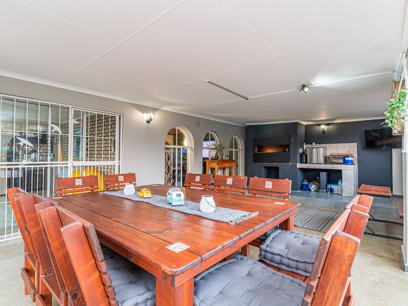 Covered patio area featuring a built-in braai, tiled flooring, and arched windows, providing a functional space for outdoor dining and entertainment.