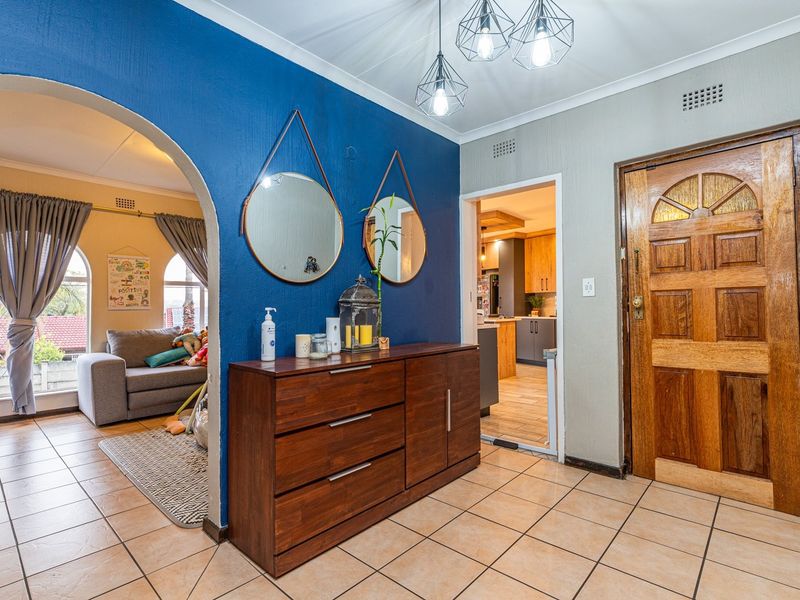 Welcoming entrance hall featuring ceramic floor tiles, a solid wood front door, and an arched opening leading into the living area.