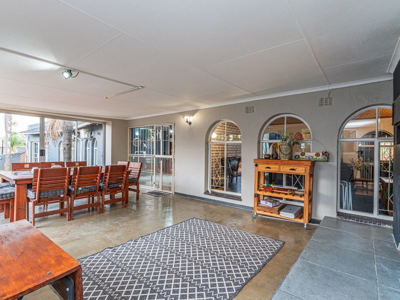 Spacious covered patio featuring tiled flooring, built-in fireplace, and arched windows, providing a versatile outdoor entertainment area with direct access to the garden.