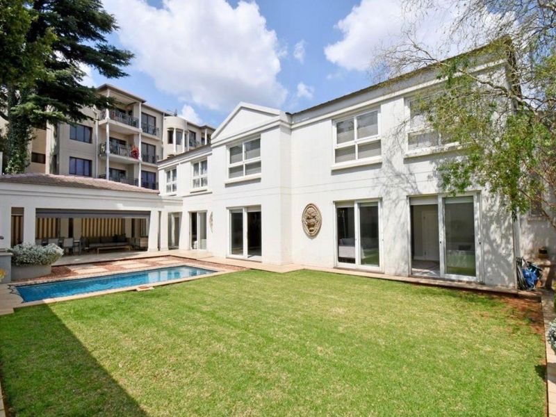 Rear view of the townhouse featuring a well-maintained lawn, a swimming pool, and a covered patio area with sliding door access.
