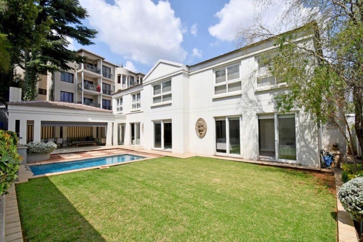 Rear view of the townhouse featuring a well-maintained lawn, a swimming pool, and a covered patio area with sliding door access.