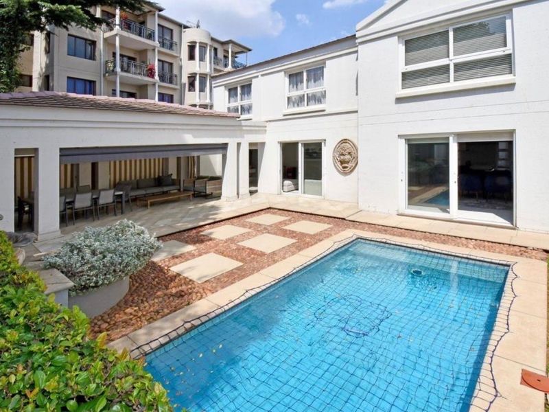 A well-maintained rear courtyard featuring a swimming pool, paved patio area, and a covered outdoor entertainment space with direct access to the home.
