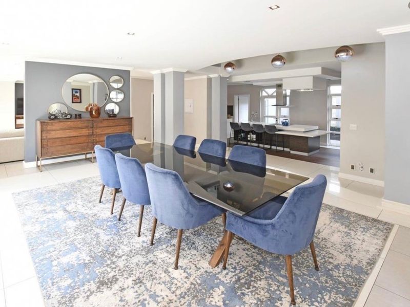 Spacious open-plan dining and kitchen area featuring modern cabinetry, a central island, recessed lighting, and sleek tiled flooring throughout.