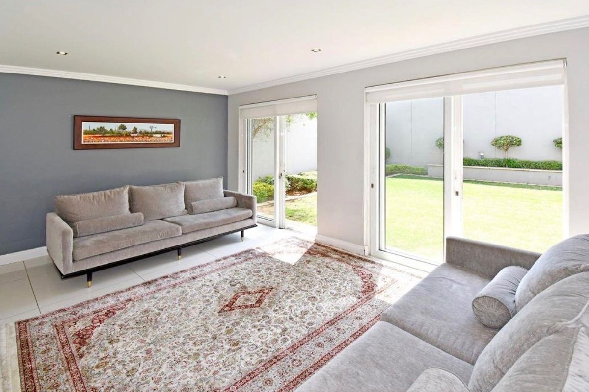 Bright living room featuring tiled flooring, recessed downlights, and large sliding glass doors providing direct access to the rear garden.